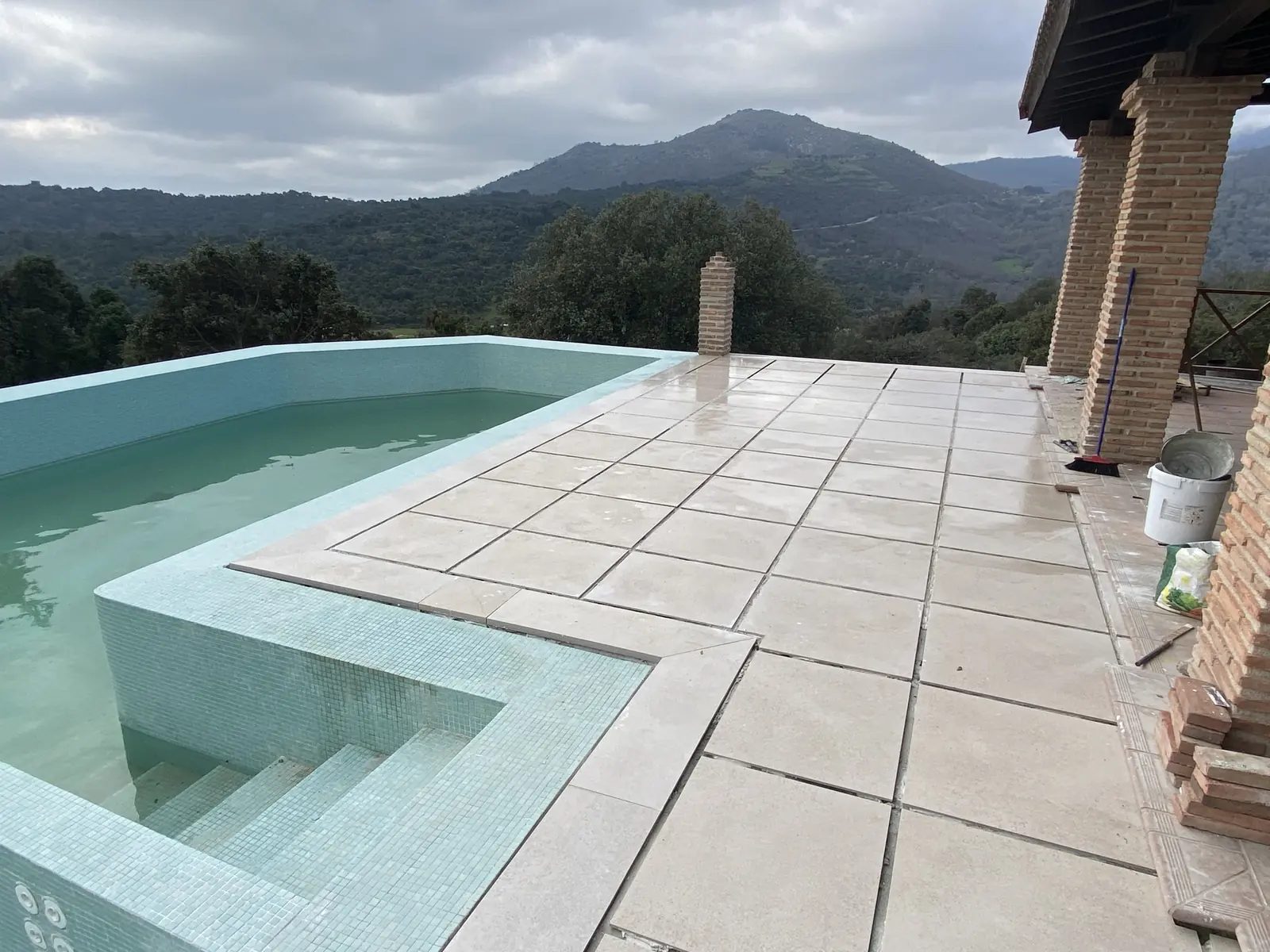 Escalera de obra y playa de piedra de la terraza, con la sierra al fondo