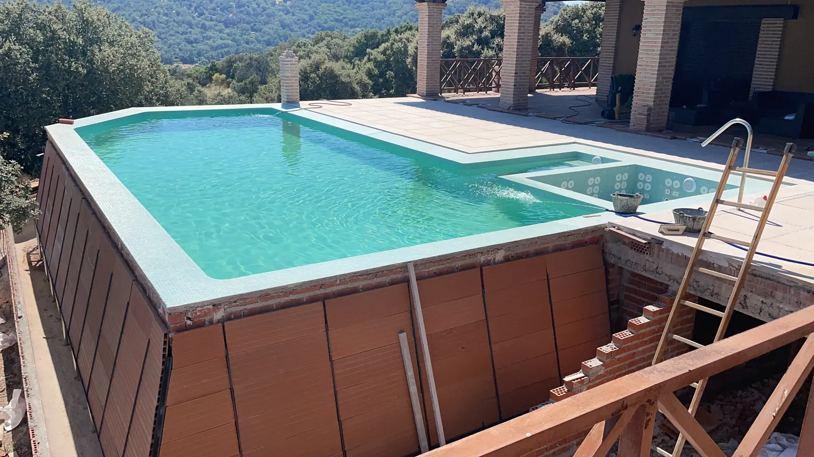 Piscina de la finca llena, con agua turquesa y la sierra al fondo en un día soleado