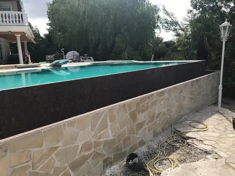 El agua vierte en toda la longitud del borde sobre el paño de mosaico oscuro.