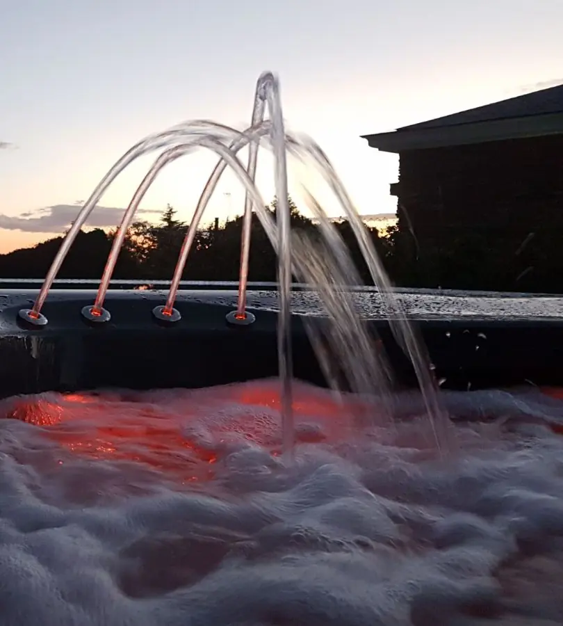 Spa iluminado con cascadas al atardecer junto a la lámina infinita